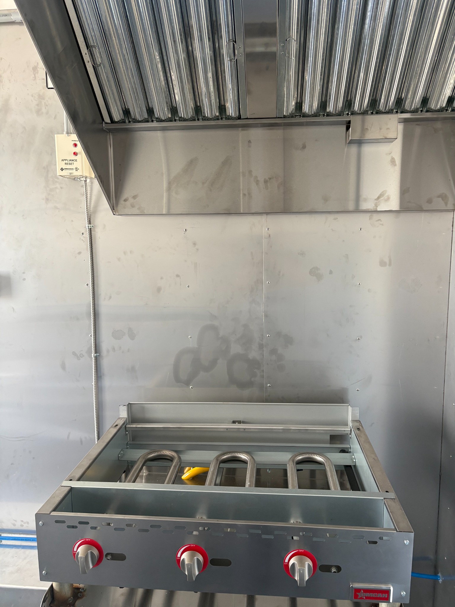 Gas grill below the commercial exhaust hood